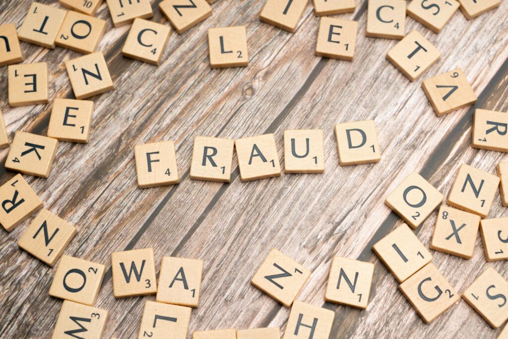 pexels photo 19835552 19835552 Alphabet tiles arranged to spell 'fraud' on a wooden surface, symbolizing deception.